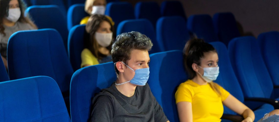 Group of people watching movie in the cinema after Coronavirus loosening measures.